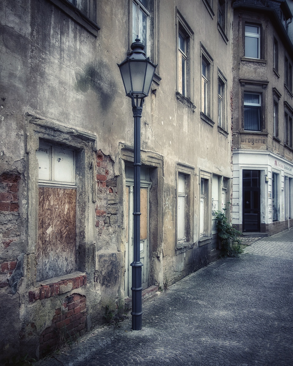 Graue Straßenlaterne vor grauen Fassaden