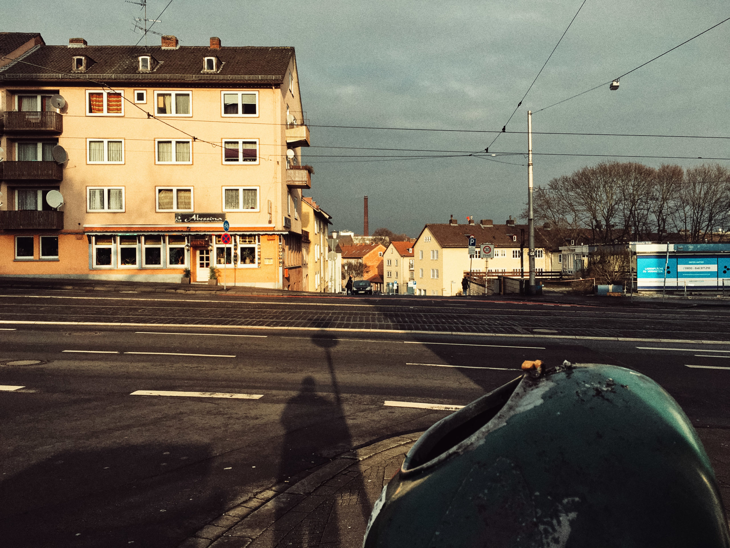 Kassel Straße mit Schienen mit Schatten des Photographen, anbei ein Mülleimer mit Zigarettenkippen